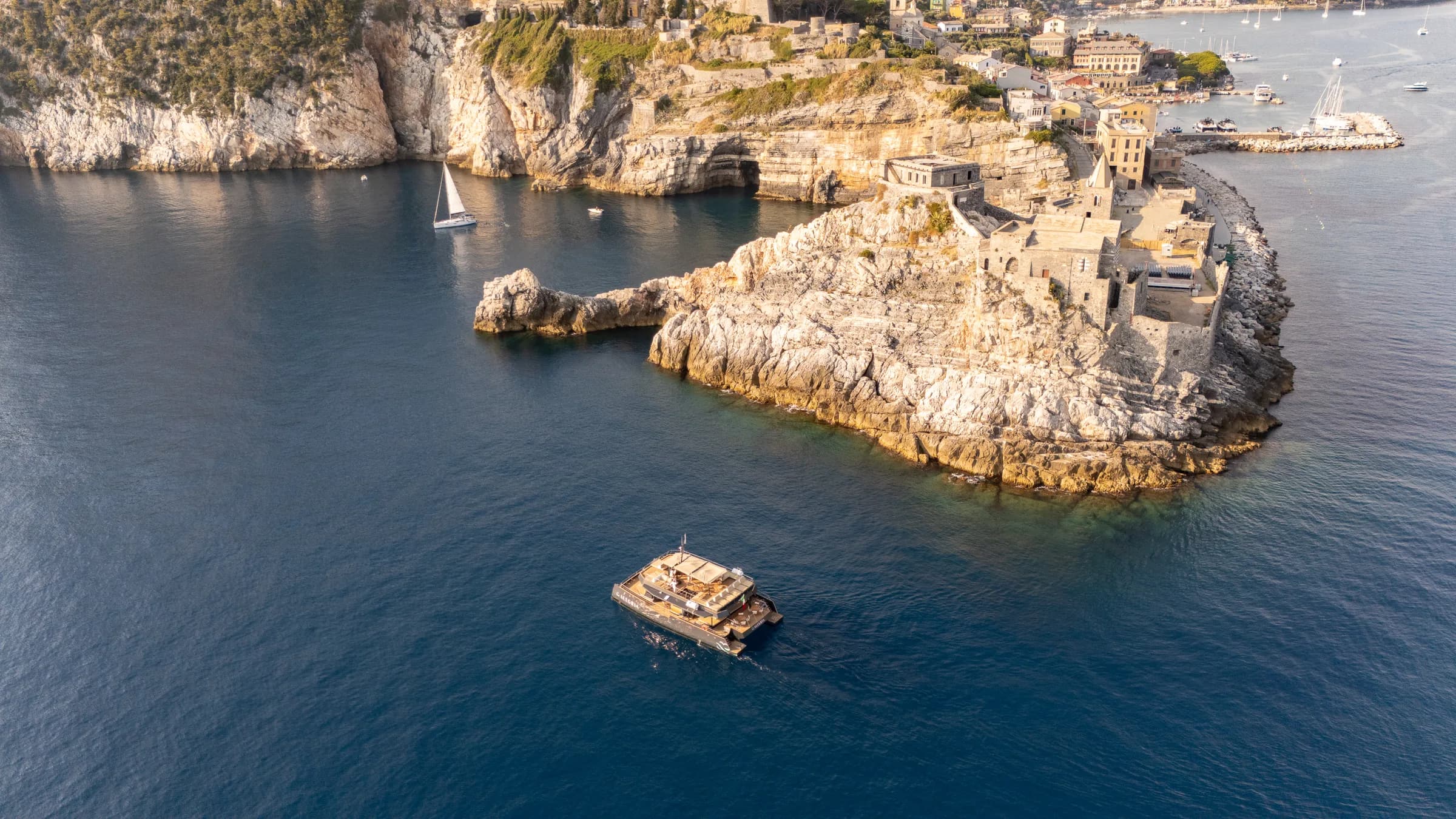 Il catamarano Alegria all'ancora sotto la costa rocciosa del golfo, ripreso dal drone