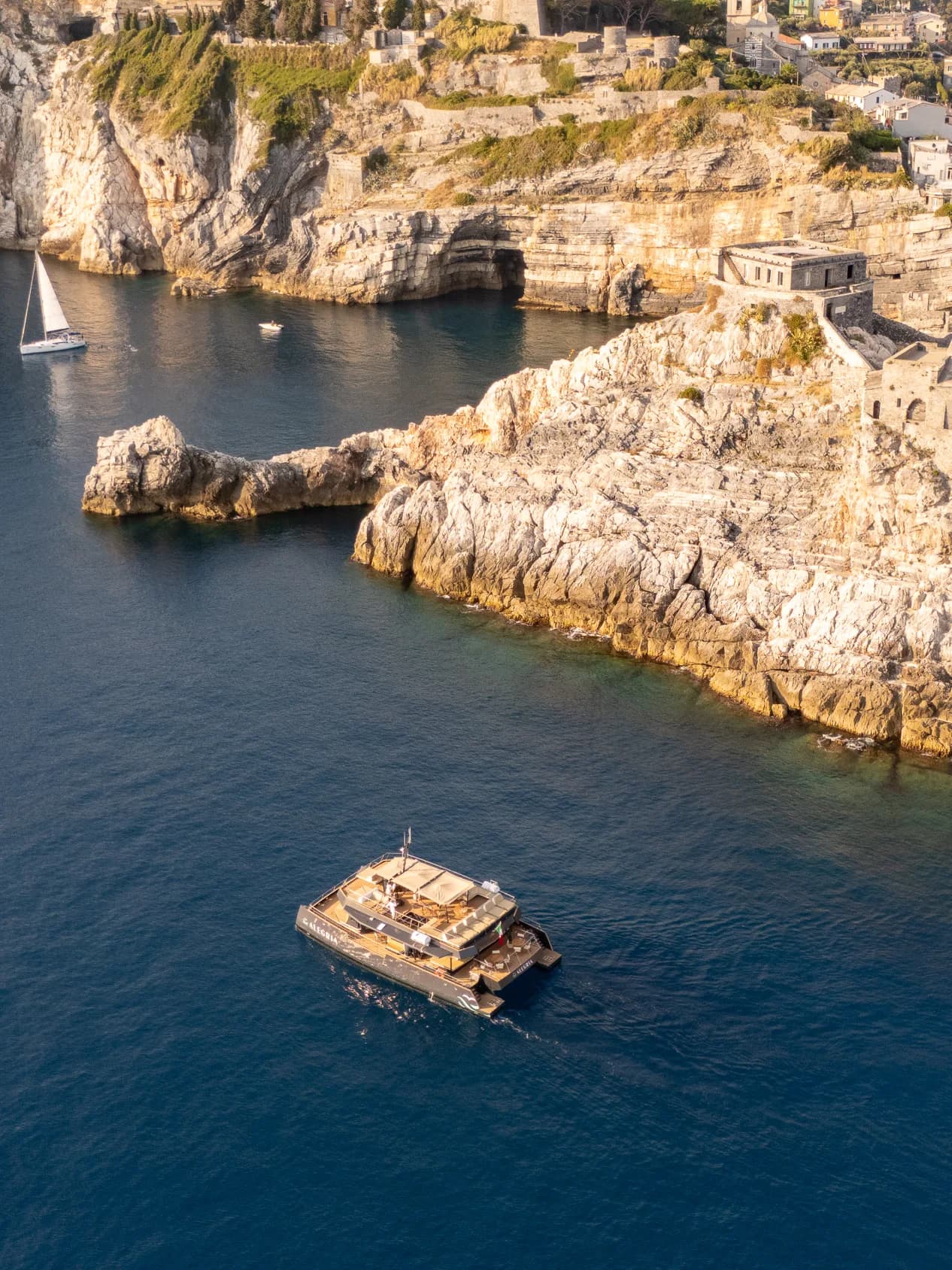 Il catamarano Alegria all'ancora sotto la costa rocciosa del golfo, ripreso dal drone