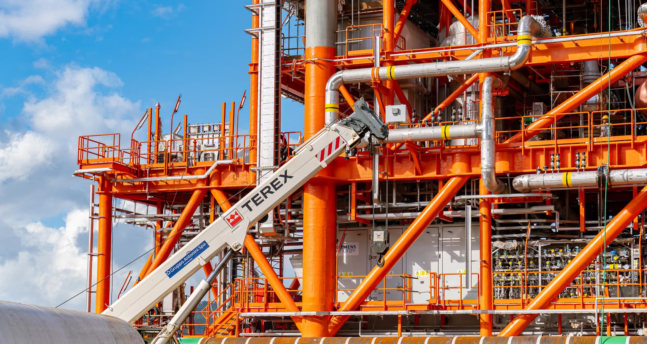 La struttura offshore in acciaio arancione nel cantiere Antonini, con la gru accanto
