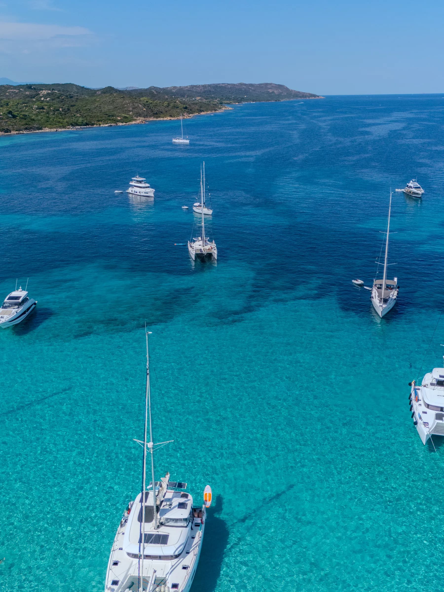 Barche a vela e catamarani all'ancora in una rada dalle acque turchesi alla Maddalena
