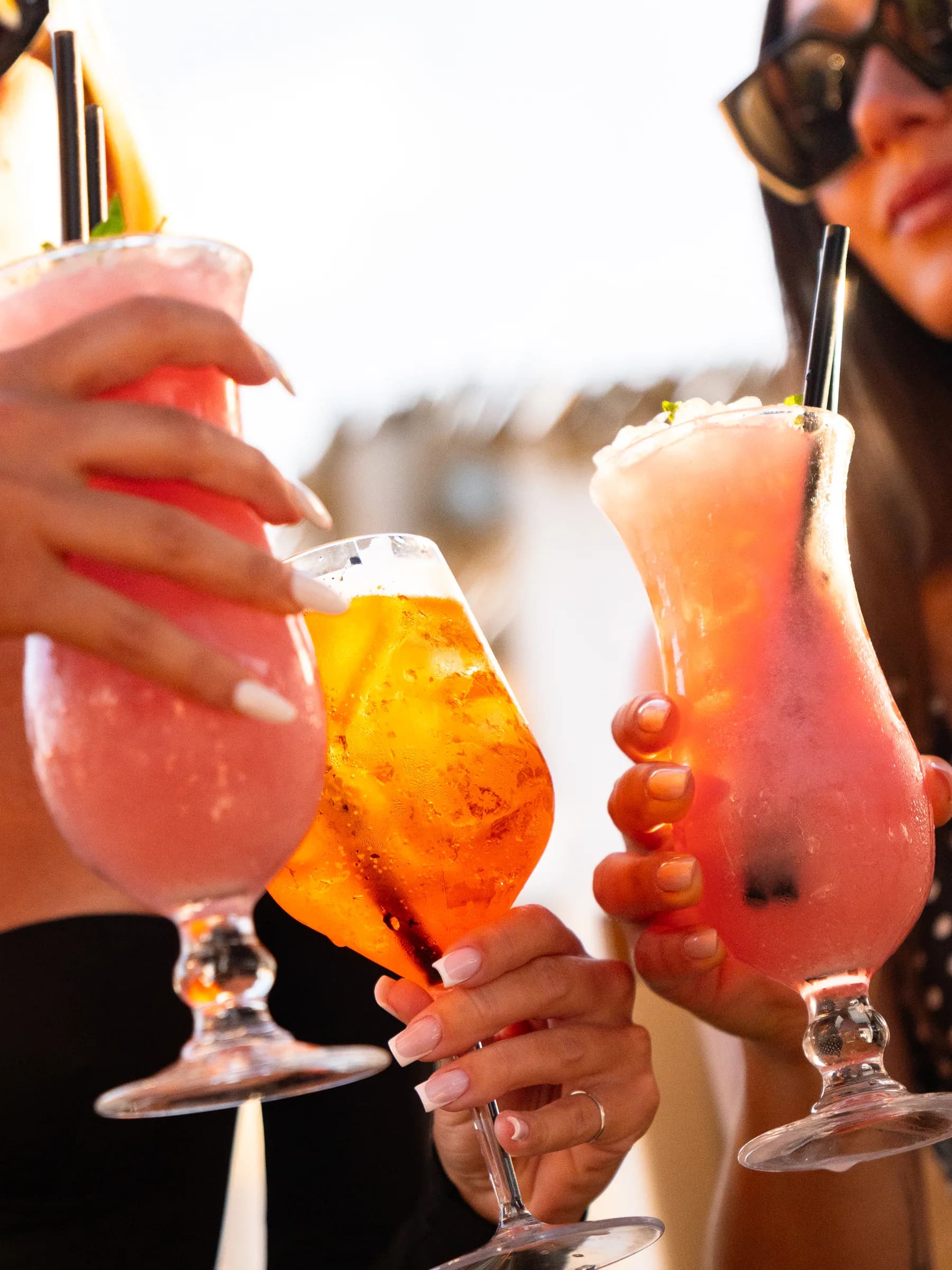 Tre cocktail alzati in un brindisi al bar del beach club