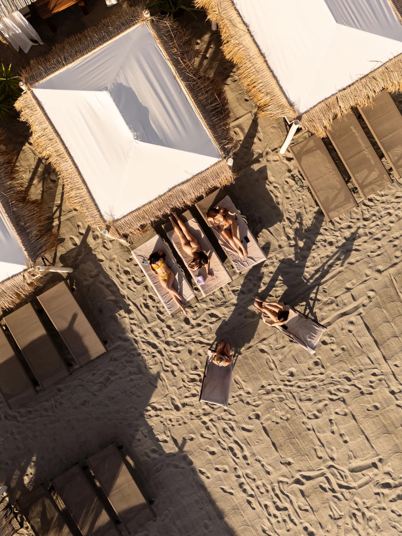 I gazebo del beach club sulla spiaggia ripresi dal drone, con le ombre lunghe del pomeriggio