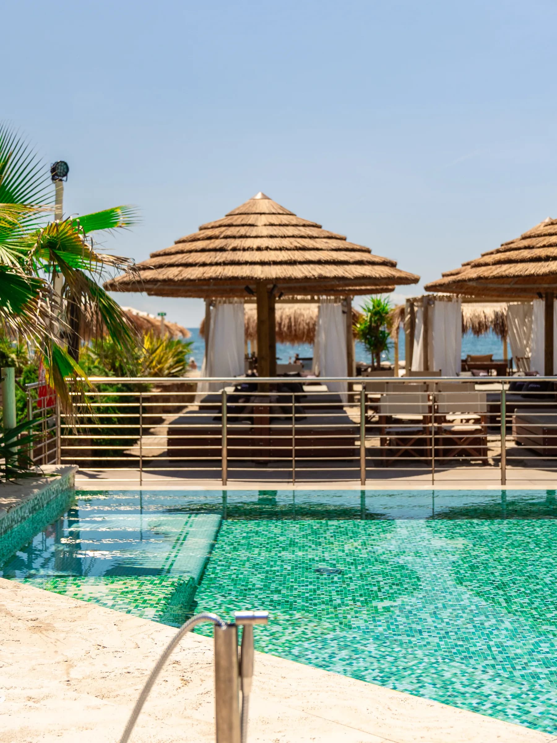 Piscina del beach club con capanne di paglia e palme attorno
