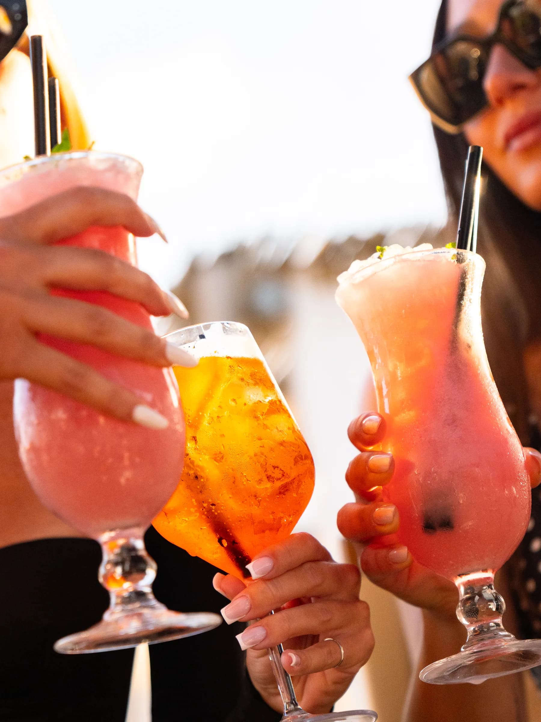 Tre cocktail alzati in un brindisi al bar del beach club