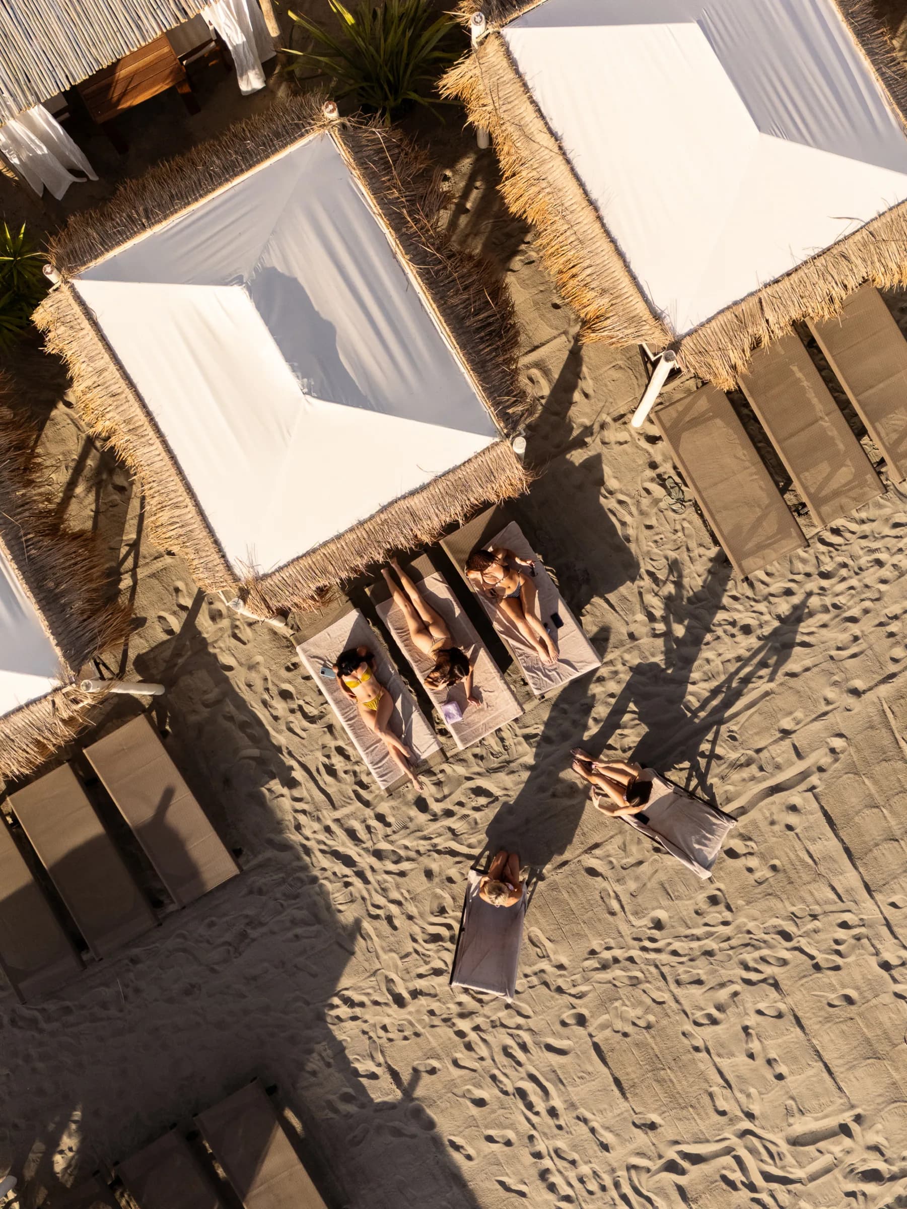 I gazebo del beach club sulla spiaggia ripresi dal drone, con le ombre lunghe del pomeriggio