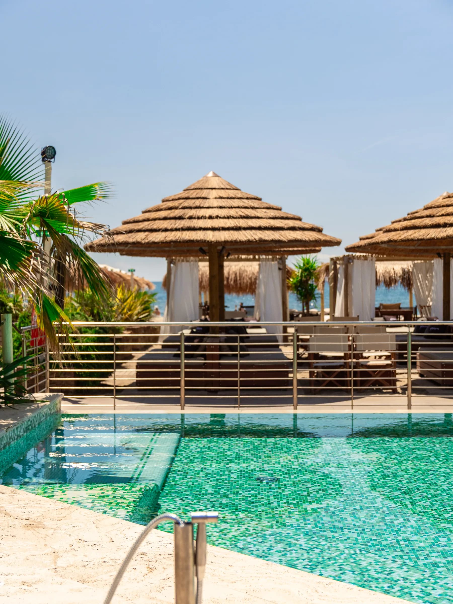 Piscina del beach club con capanne di paglia e palme attorno