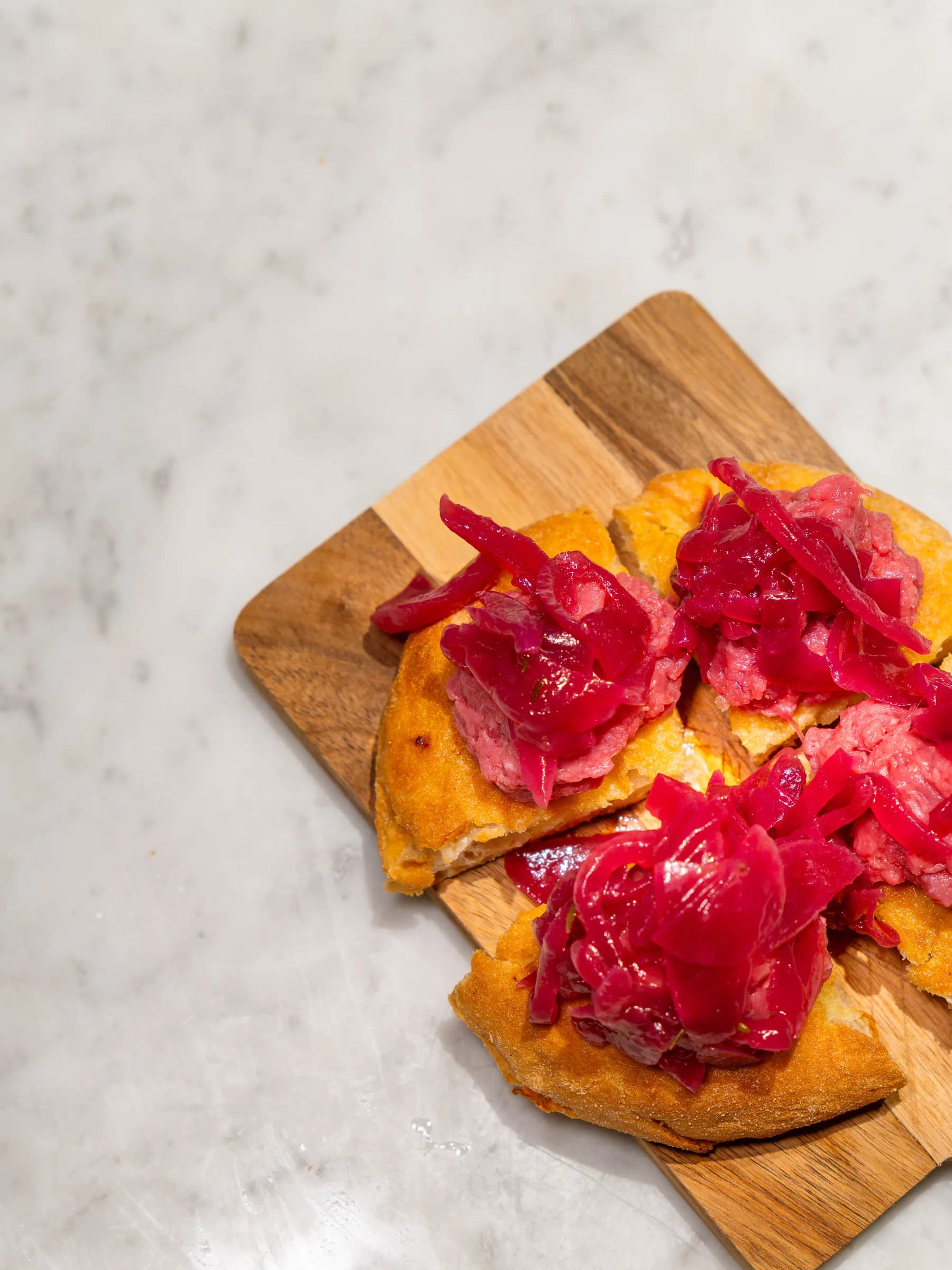 Focaccia tagliata su tagliere di legno, farcita con verdure rosse in agrodolce, servita al Pin Bon
