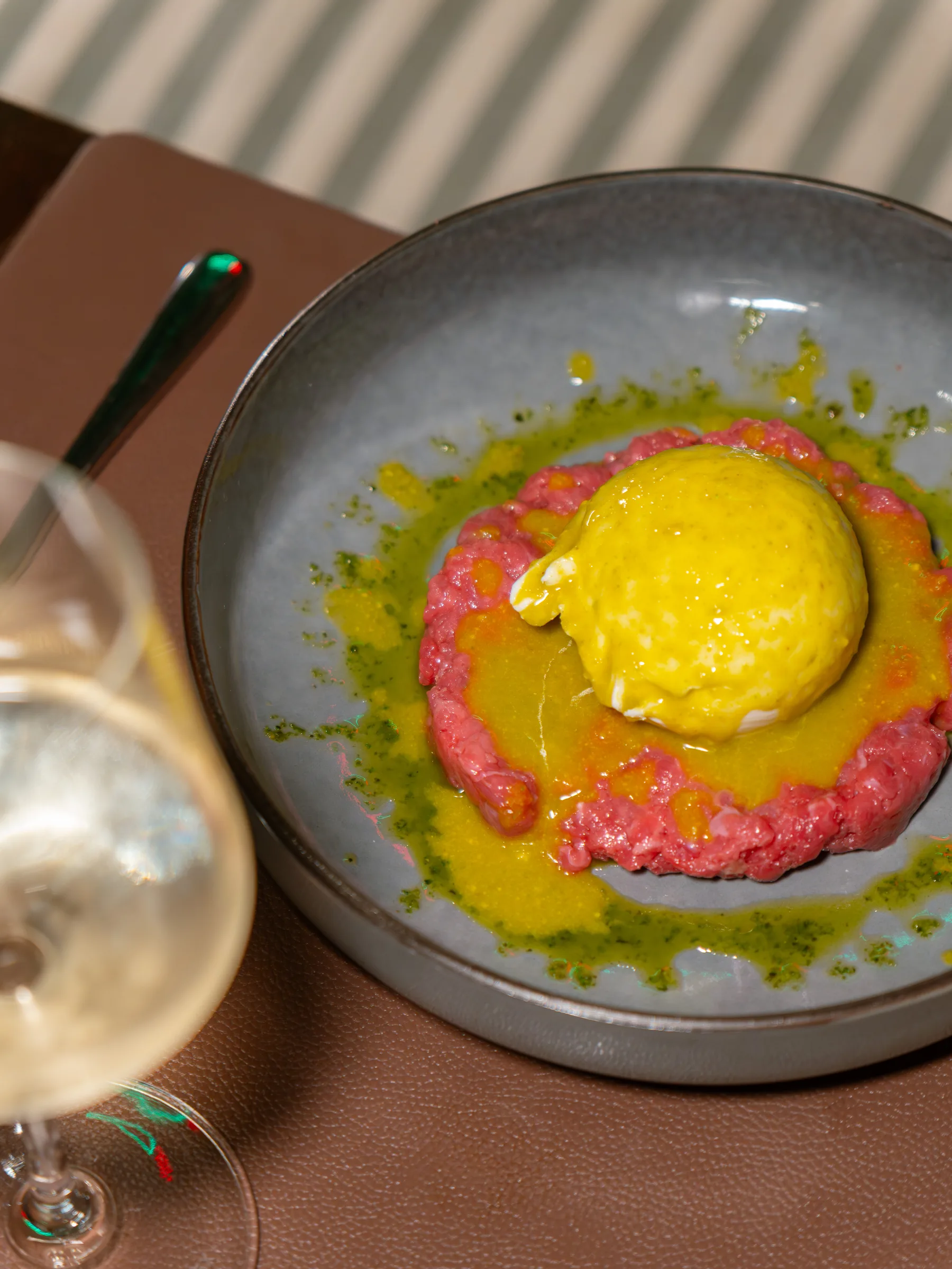 Tartare di manzo con quenelle di crema gialla e olio al basilico, servita al Pin Bon