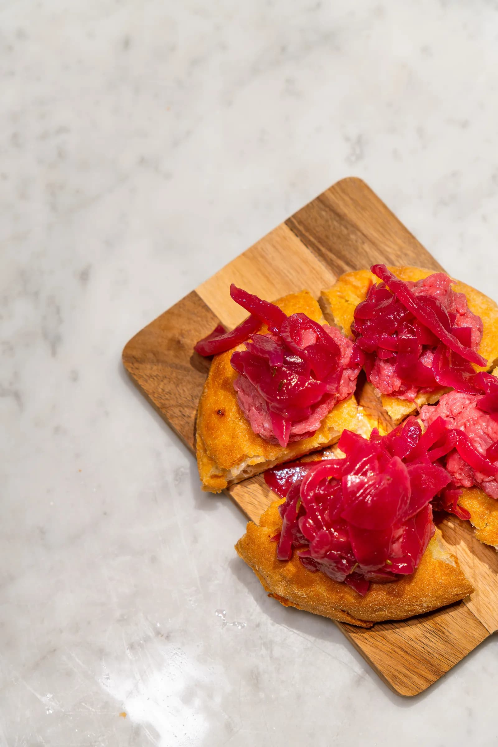 Focaccia tagliata su tagliere di legno, farcita con verdure rosse in agrodolce, servita al Pin Bon