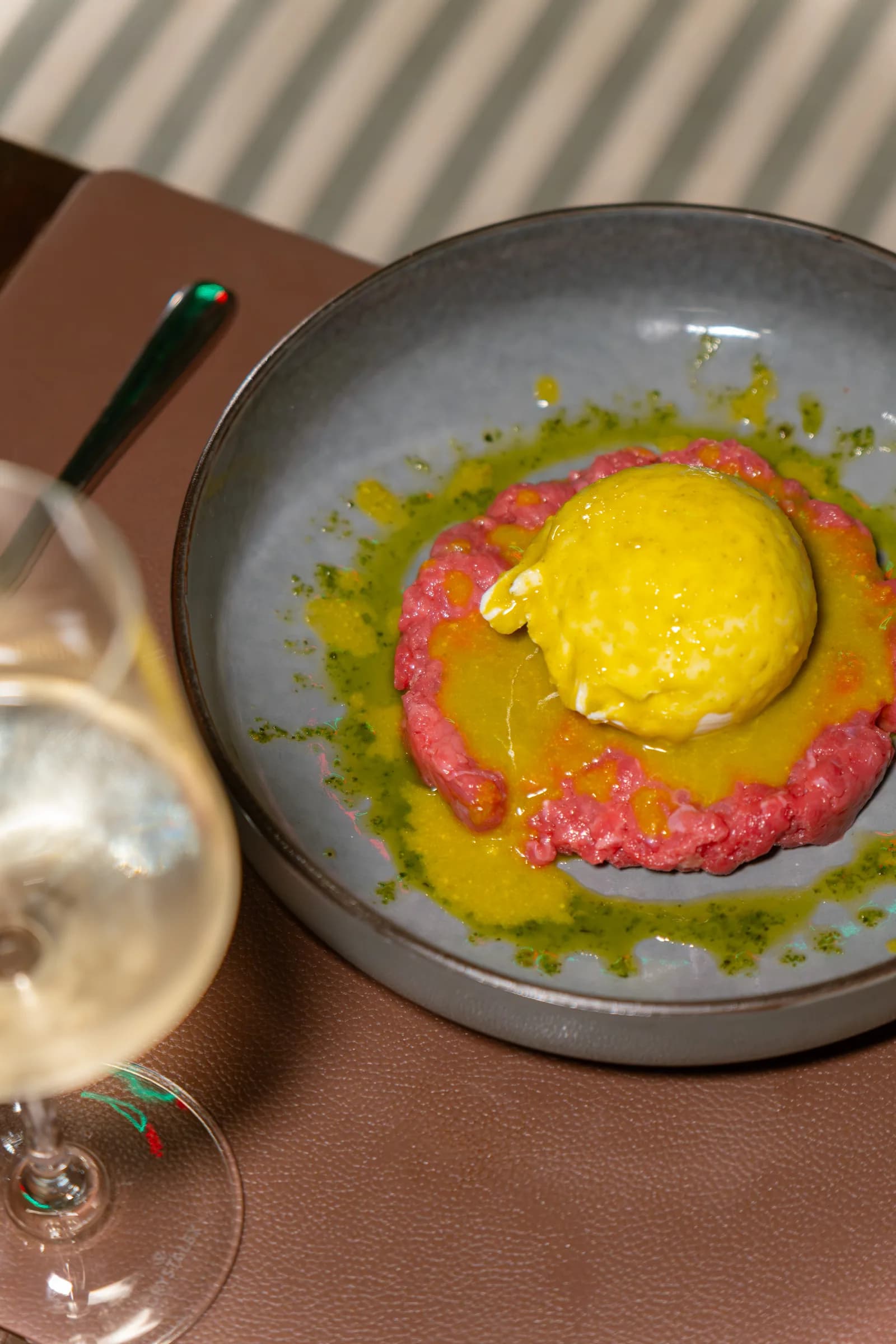 Tartare di manzo con quenelle di crema gialla e olio al basilico, servita al Pin Bon