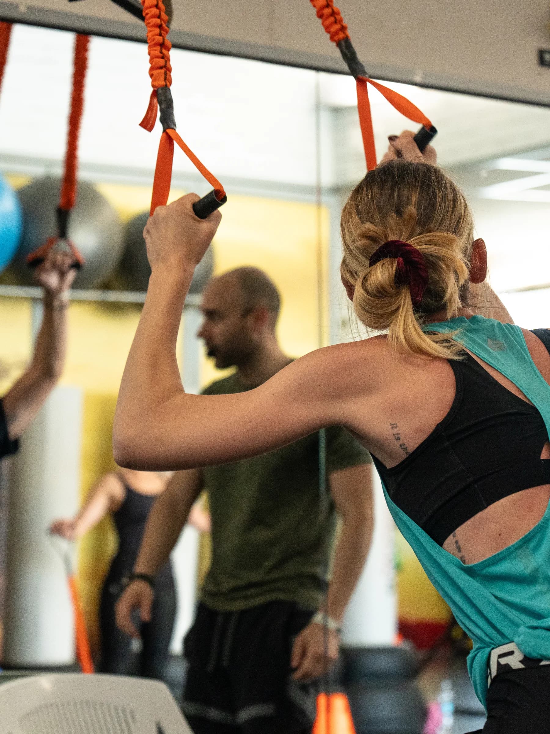 Istruttore della palestra Kleb che segue una persona durante un esercizio alle fasce sospese