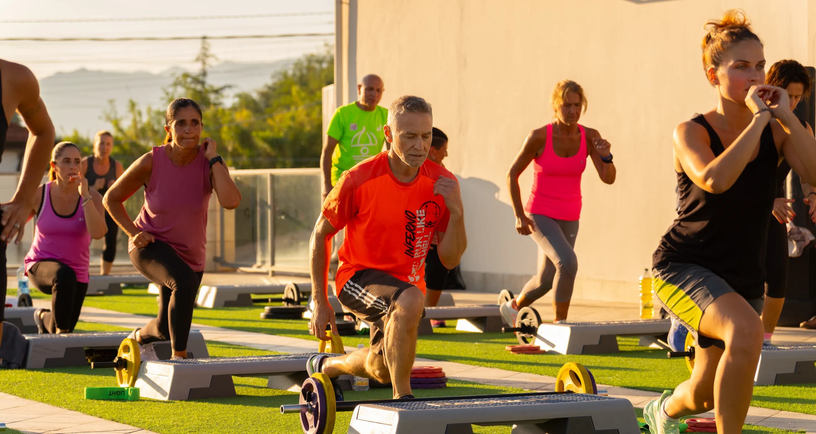 Il corso all'aperto sul prato della palestra, con il gruppo che si allena sugli step