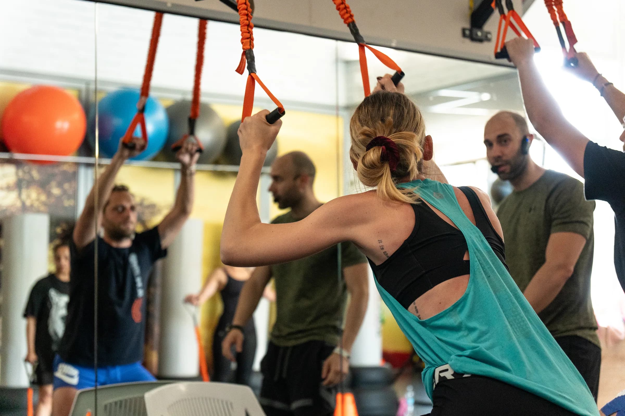 Istruttore della palestra Kleb che segue una persona durante un esercizio alle fasce sospese