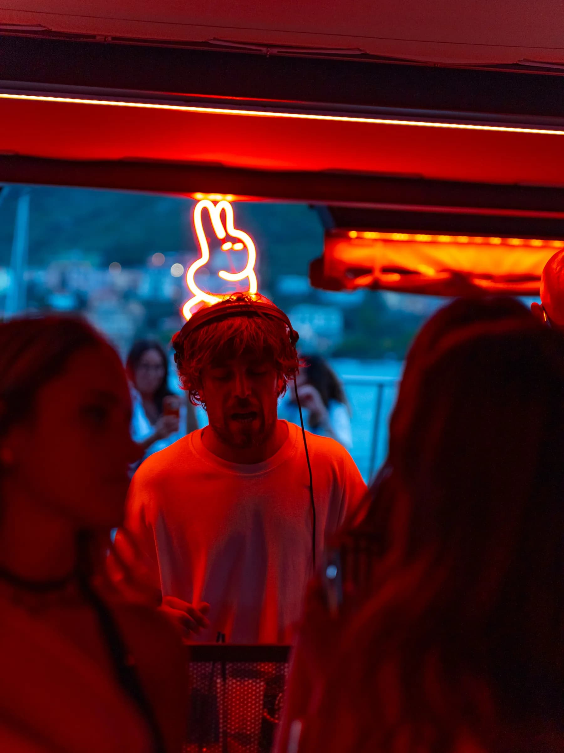 Dj alla consolle di Lazy Buns nella luce rossa, sotto l'insegna al neon a forma di coniglio