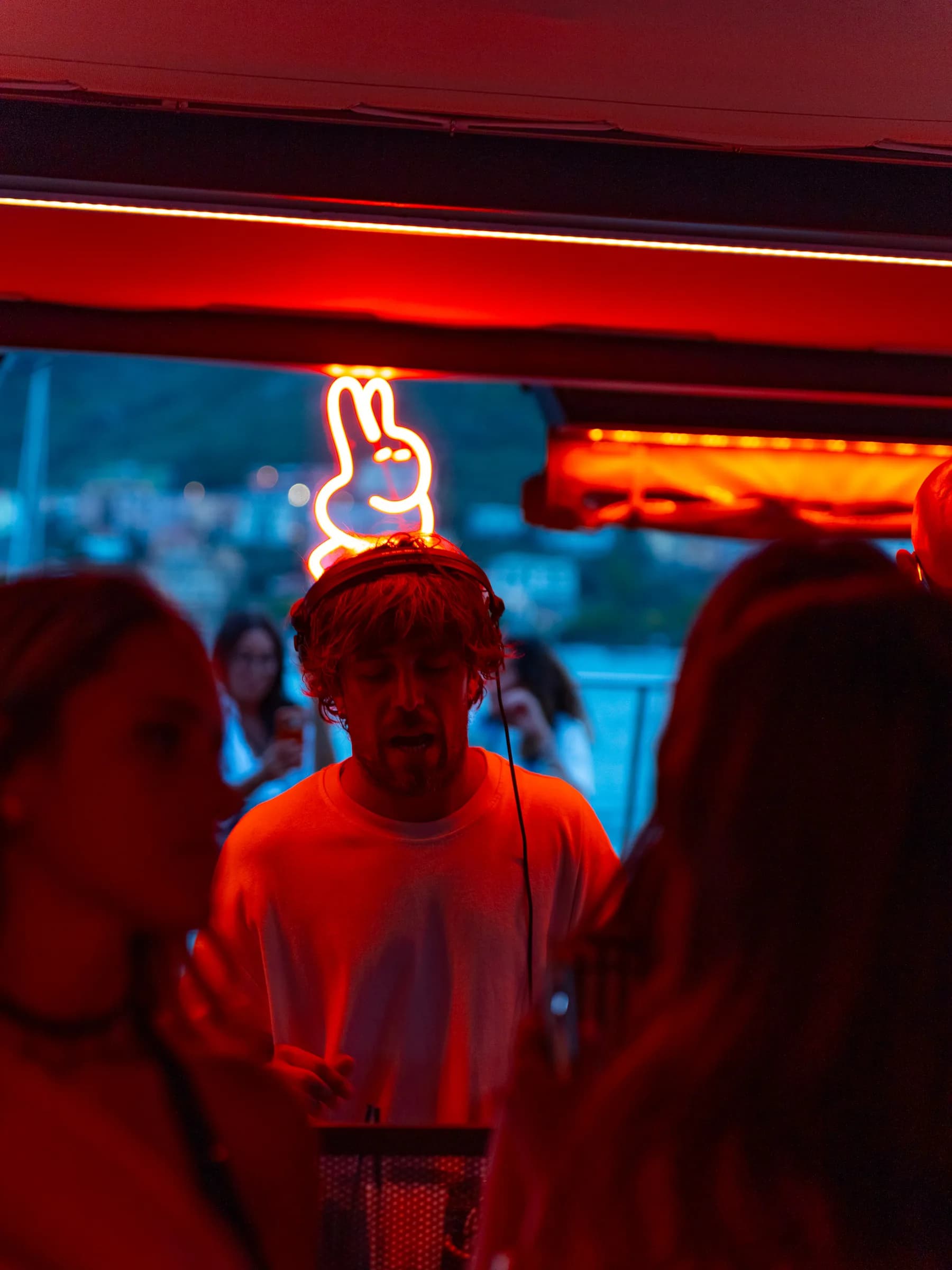 Dj alla consolle di Lazy Buns nella luce rossa, sotto l'insegna al neon a forma di coniglio