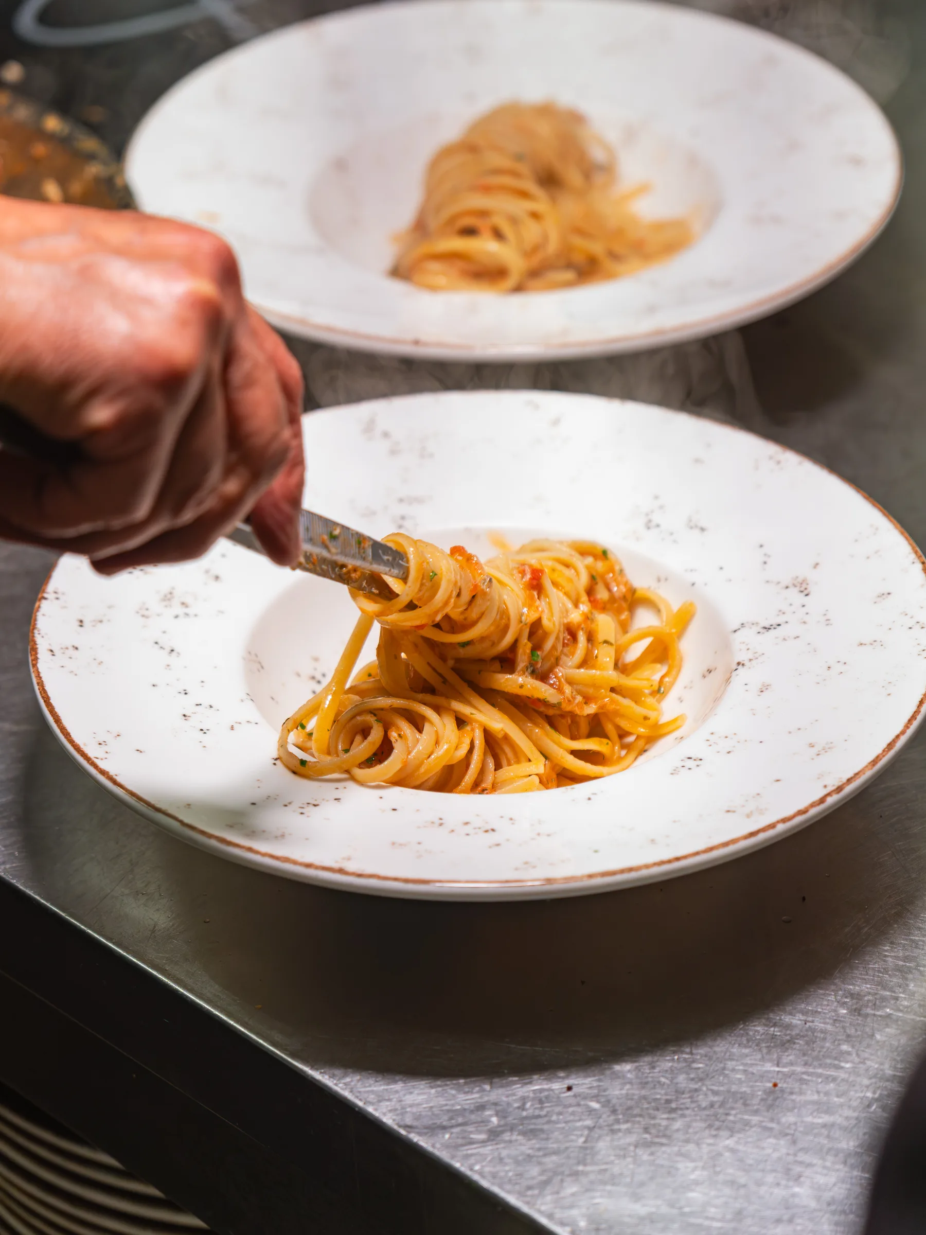Lo chef di Ottone impiatta un primo di pasta nella cucina del bistrot