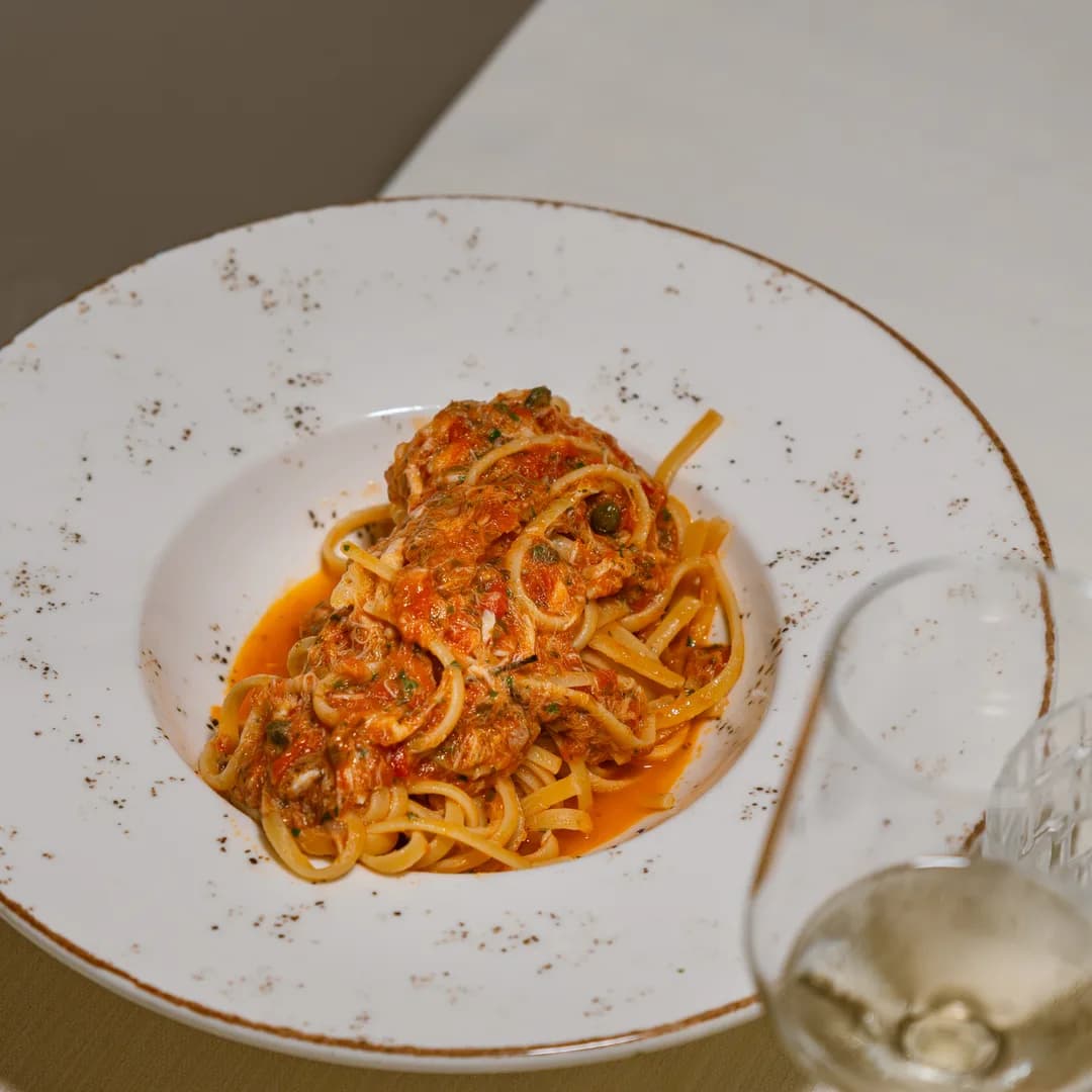 Tagliolini al ragù serviti nel piatto, con il calice di vino accanto