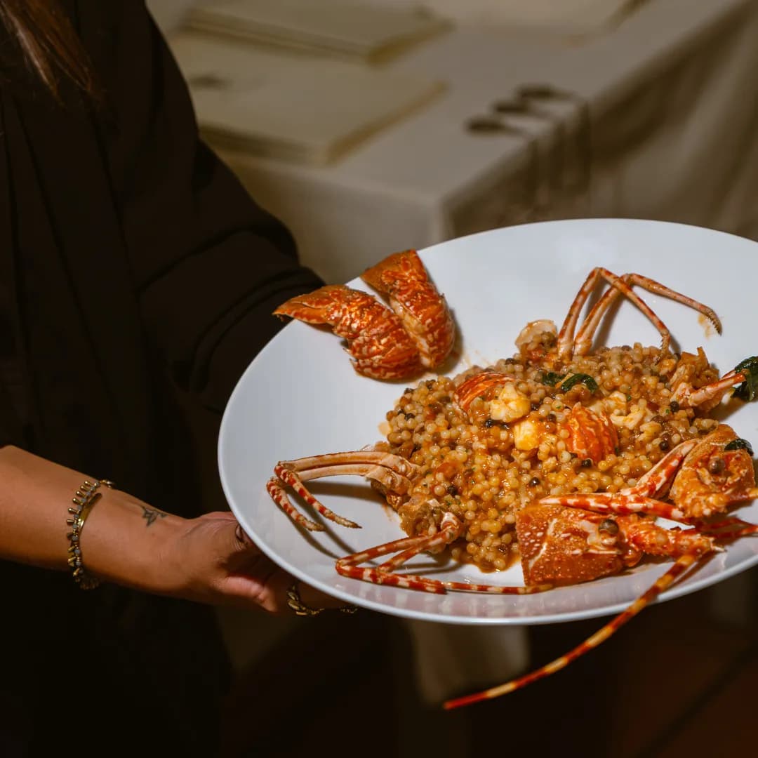 Il piatto di fregola con gli scampi portato in sala dal cameriere