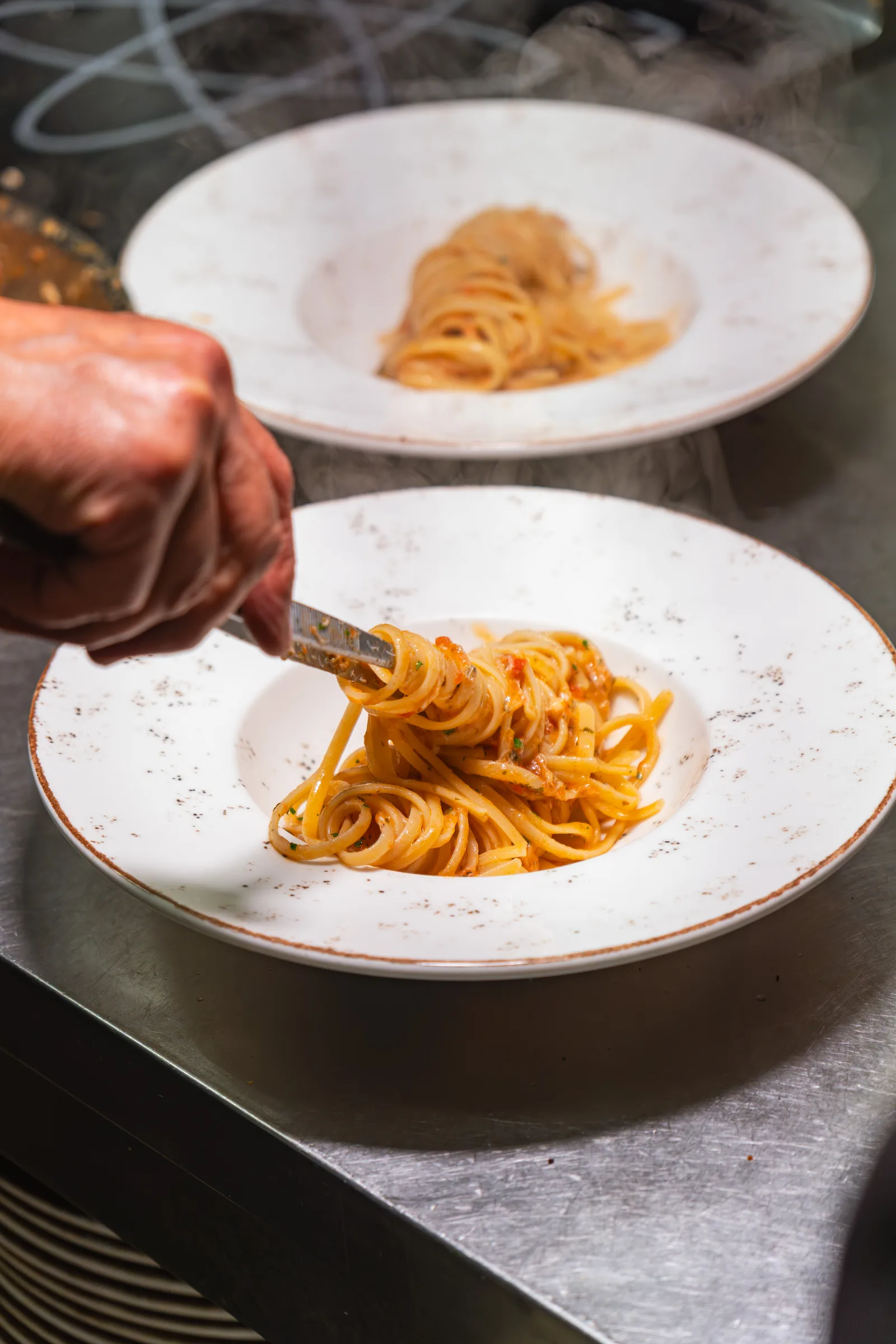 Lo chef di Ottone impiatta un primo di pasta nella cucina del bistrot
