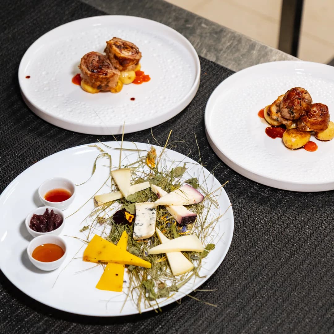 Tre piatti impiattati allineati sul tavolo nero del ristorante