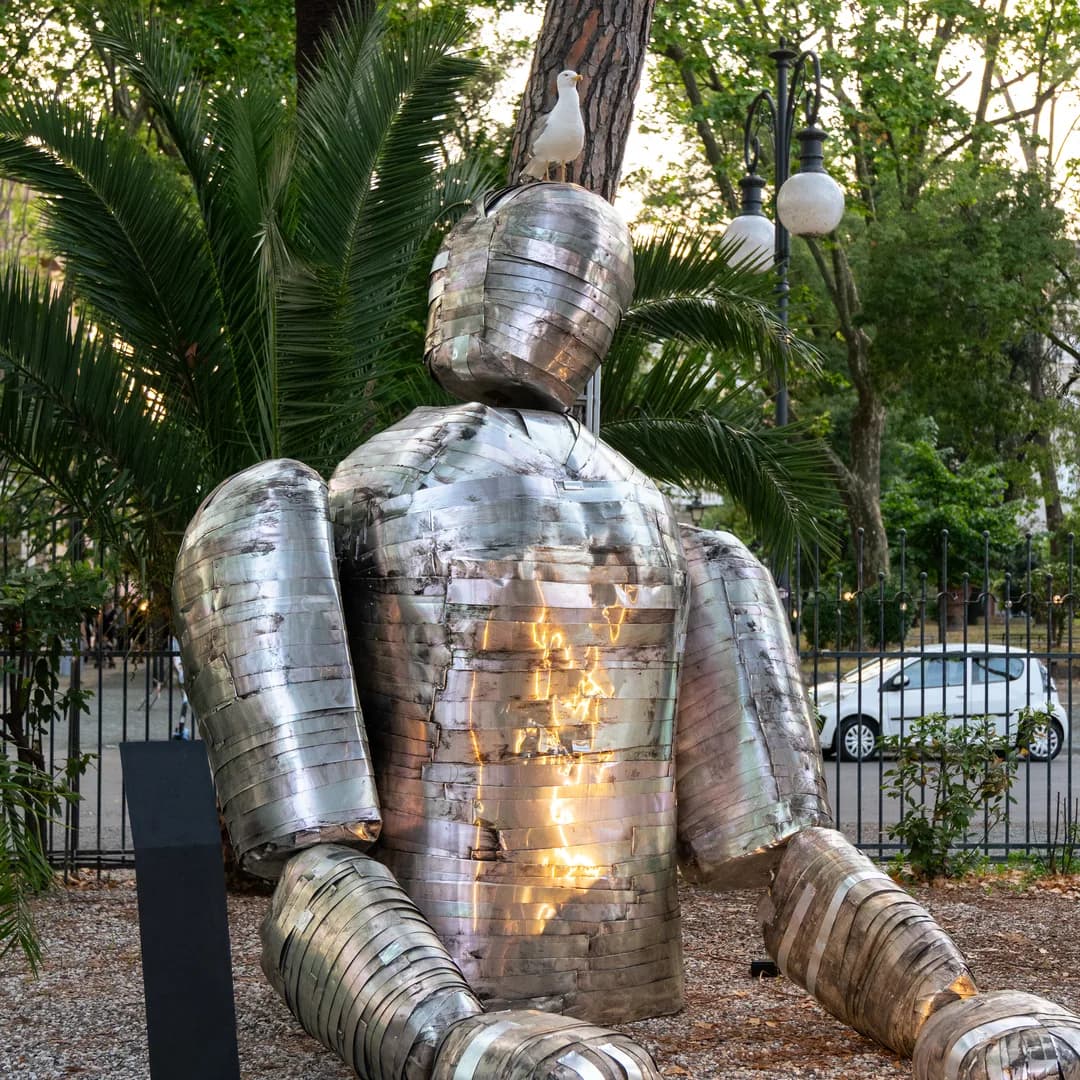 Scultura di metallo illuminata fra i pini, davanti al locale