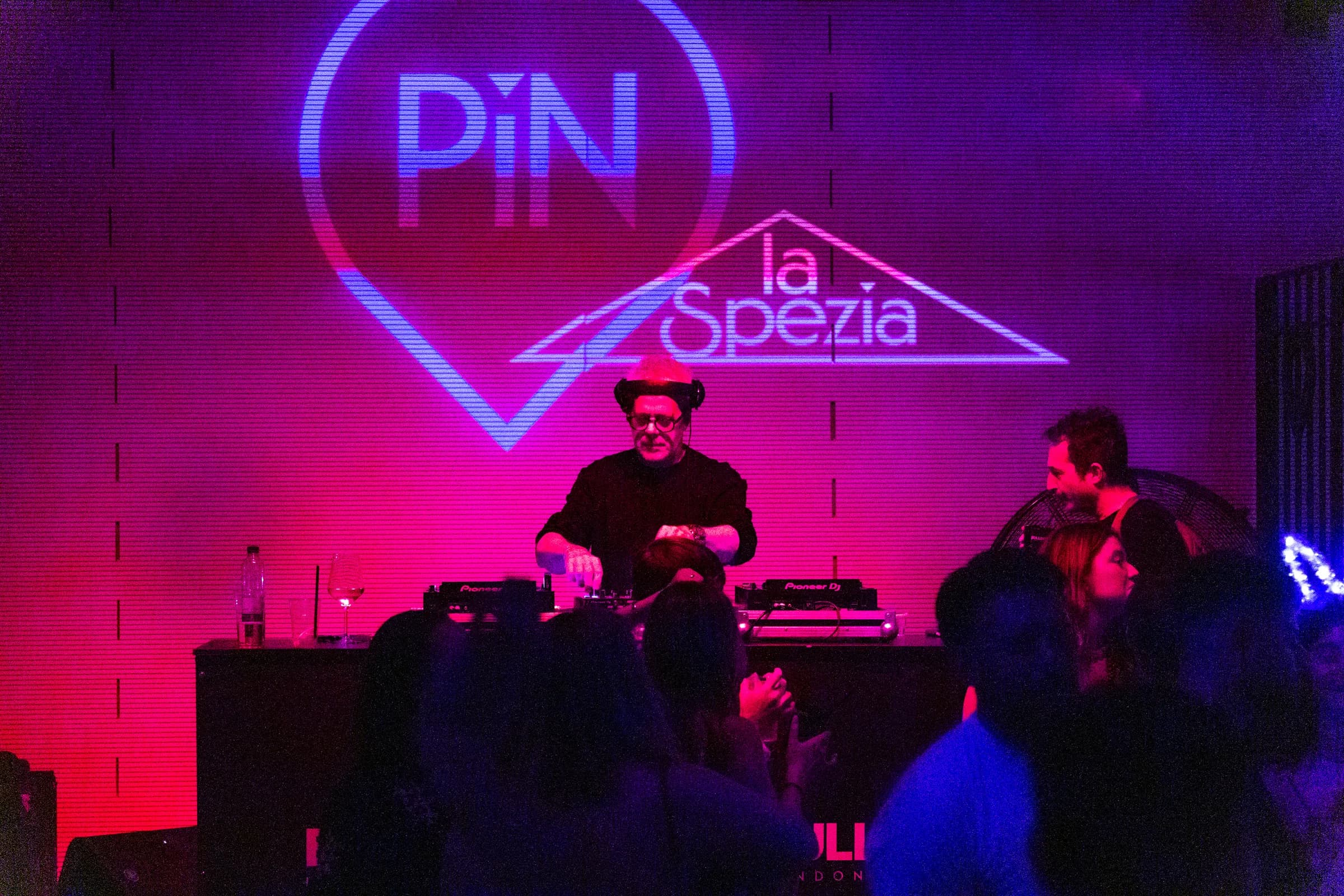 Dj set serale al PiN la Spezia davanti alla scritta al neon del locale