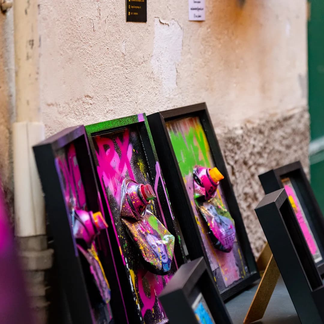 Stampe e quadri colorati appoggiati al muro di pietra