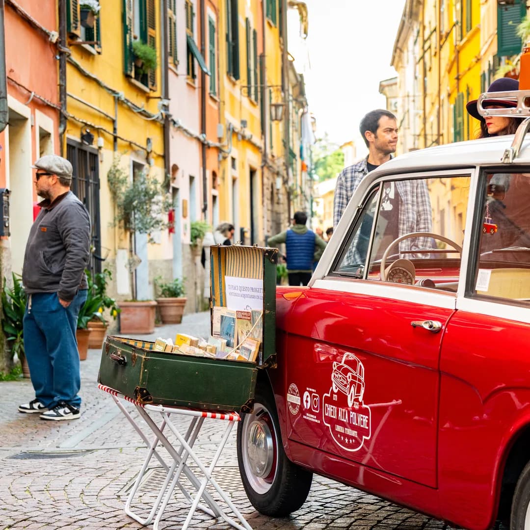 Il vicolo pieno di banchi con la Fiat rossa della libreria itinerante