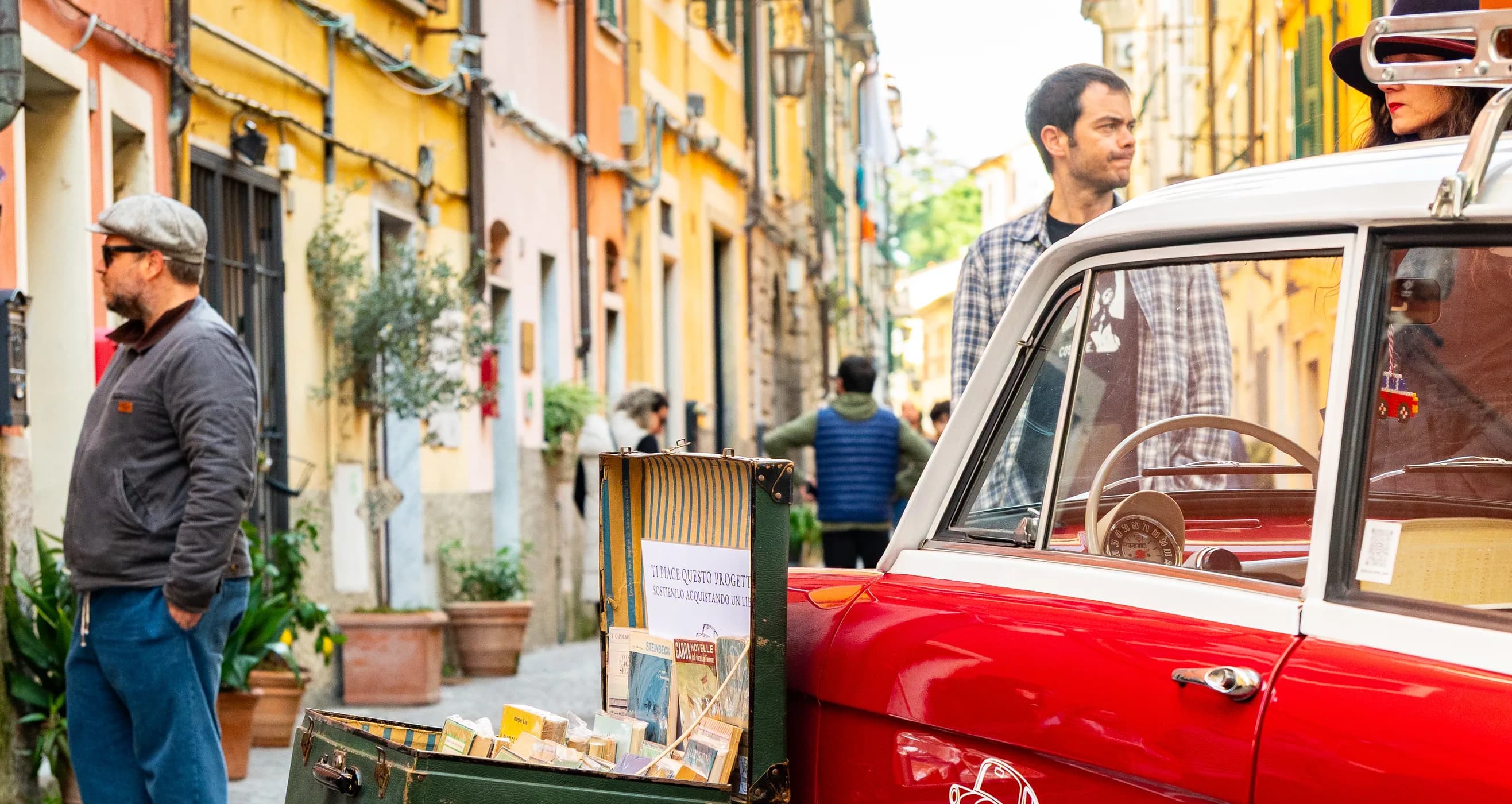 Il vicolo del centro durante il festival, con la libreria itinerante sulla Fiat rossa e i banchi