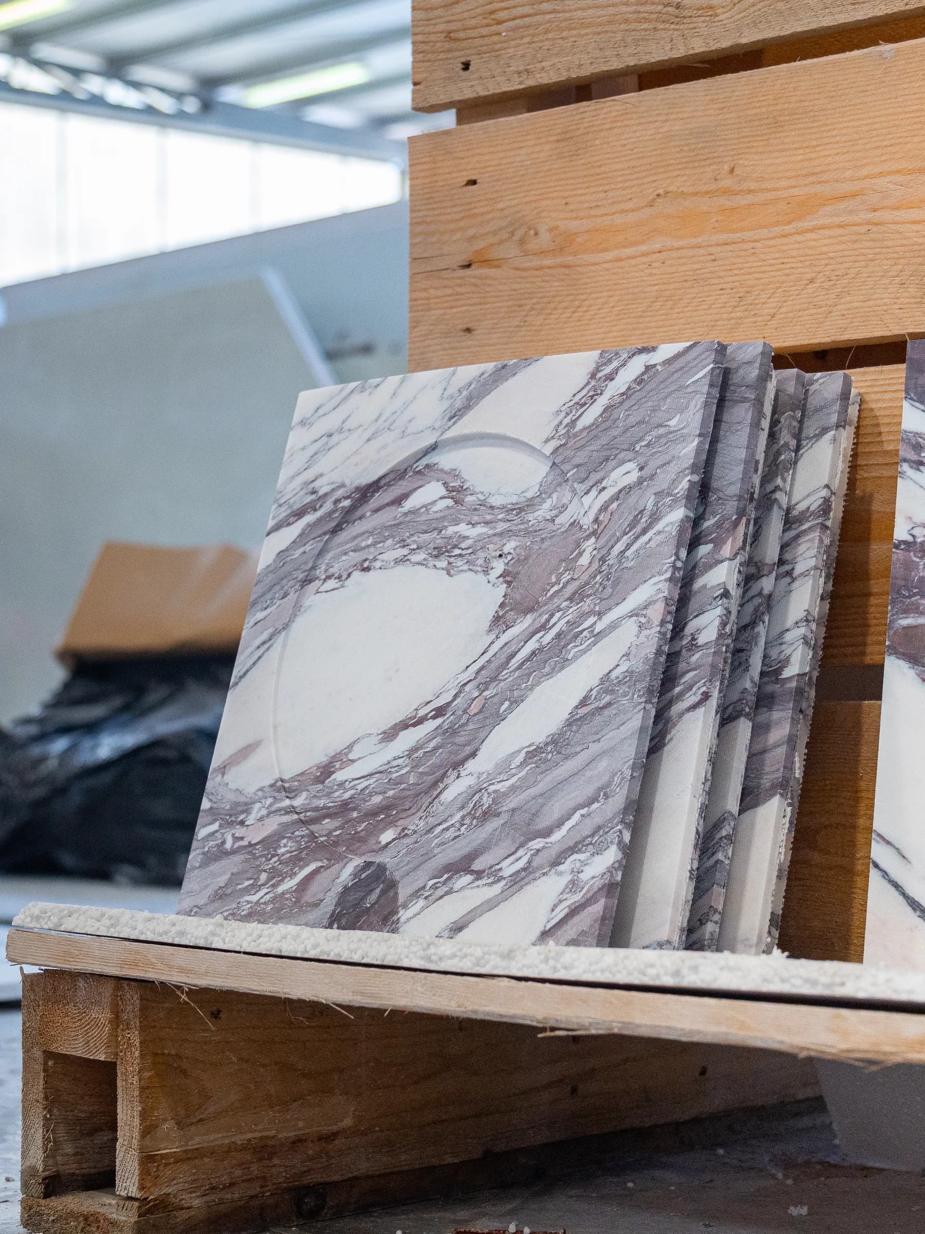 Lastre di marmo dalle venature viola appoggiate ai cavalletti di legno nel laboratorio Techno Stone
