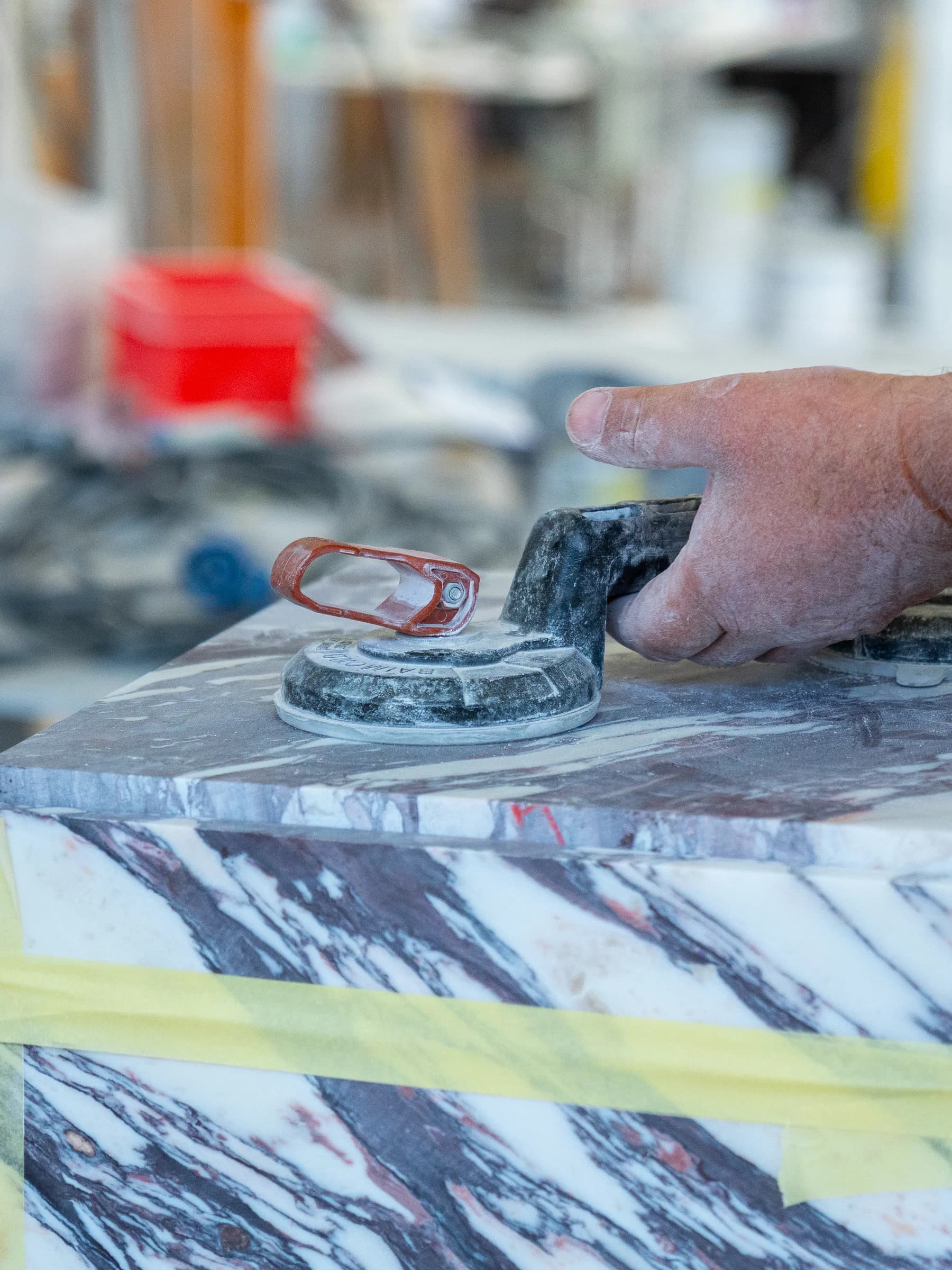 Mani al lavoro su un blocco di marmo protetto dal nastro nel laboratorio Techno Stone