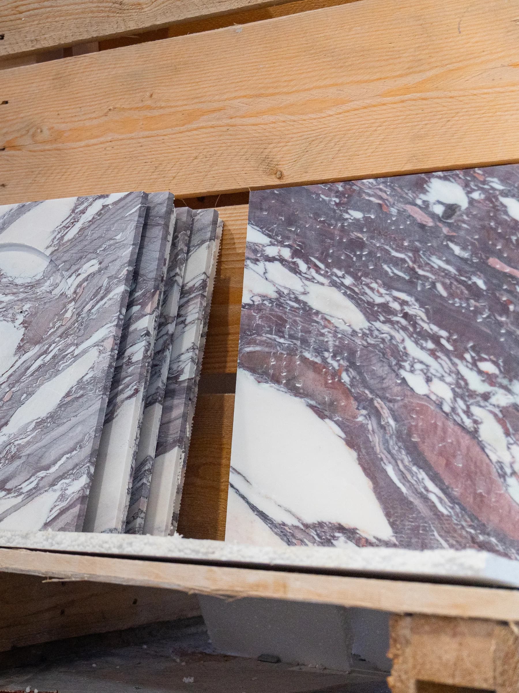 Lastre di marmo dalle venature viola appoggiate ai cavalletti di legno nel laboratorio Techno Stone