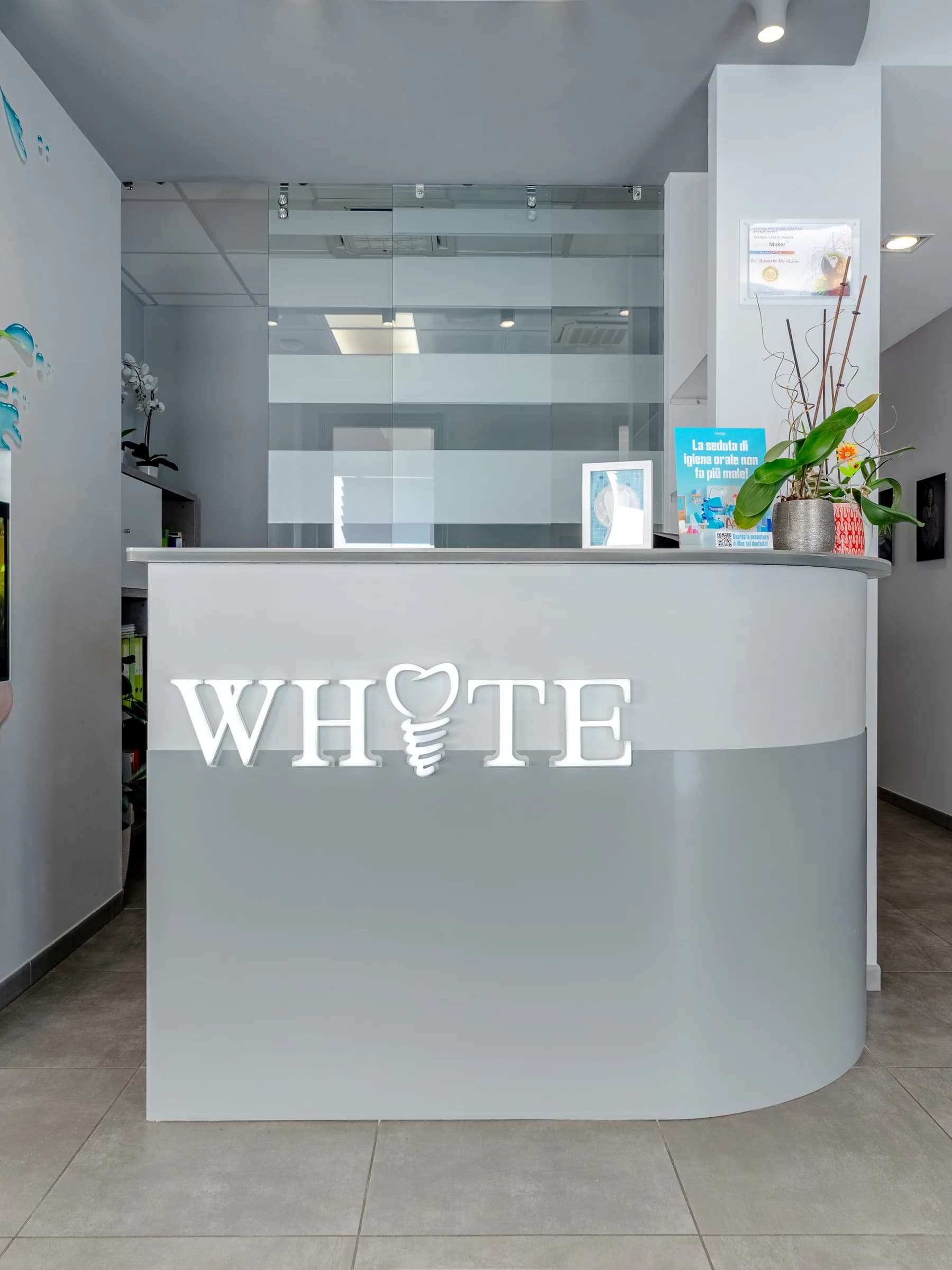 Reception dello studio dentistico White con il logo sul bancone e l'acquario a parete