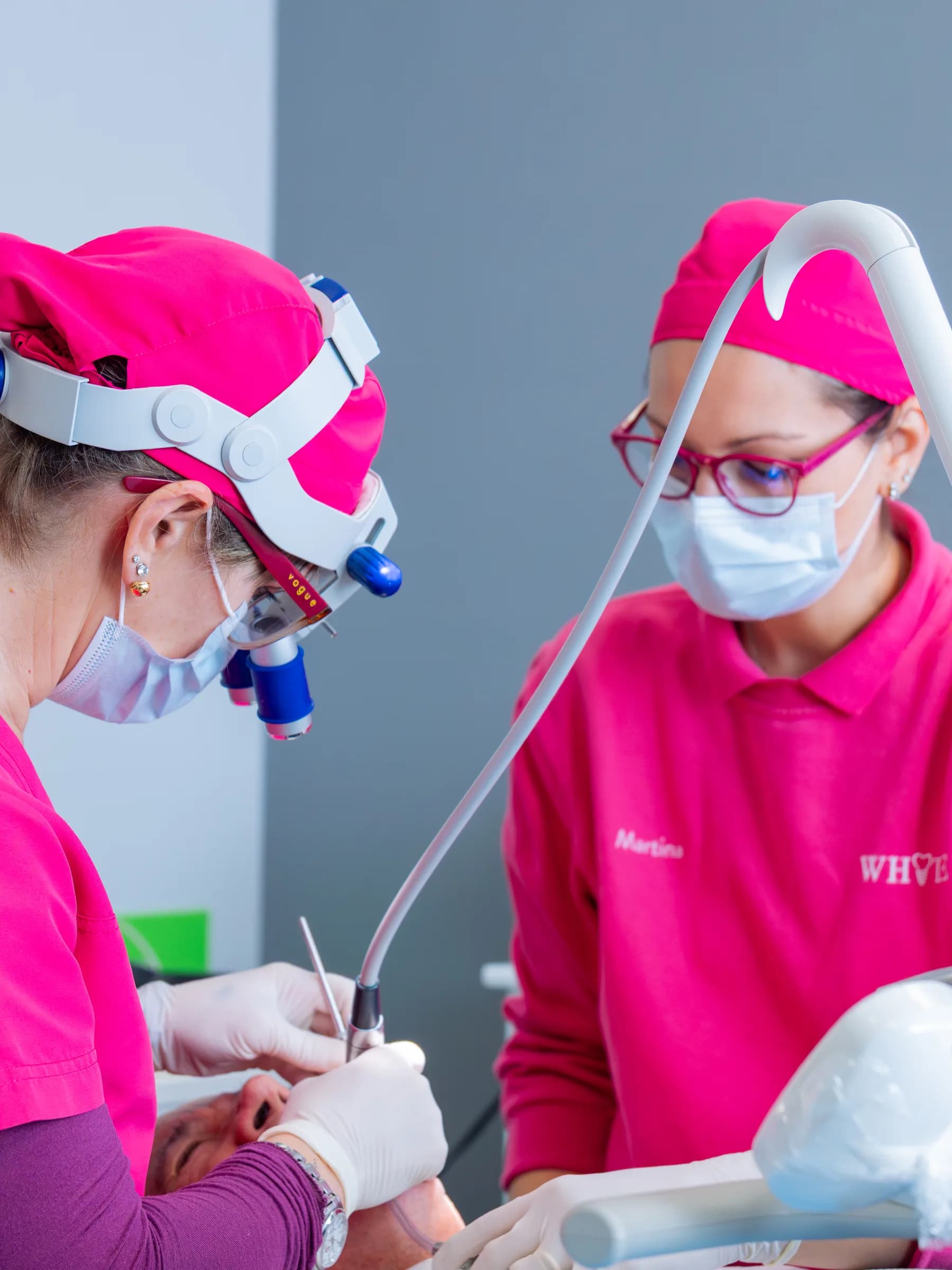Due professioniste dello studio dentistico White, in divisa rosa, al lavoro sul riunito