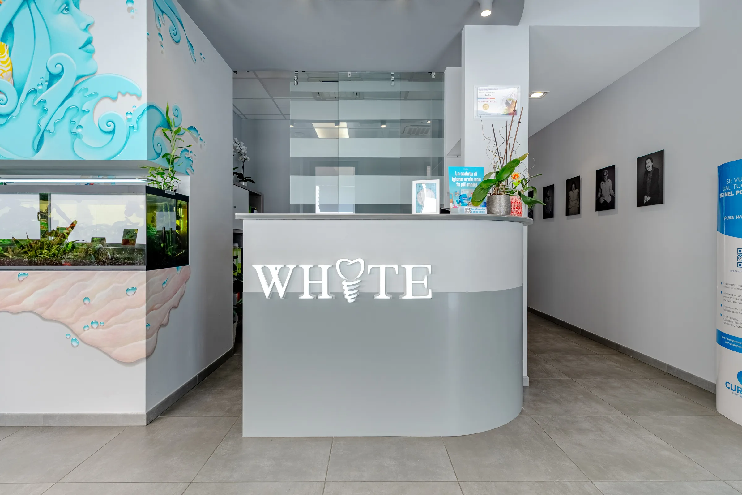 Reception dello studio dentistico White con il logo sul bancone e l'acquario a parete