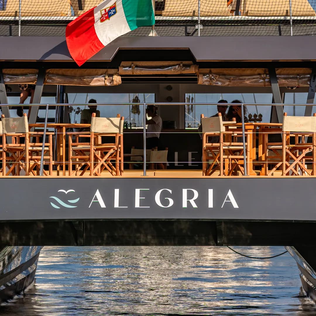 La poppa del catamarano Alegria, col nome sulla plancia e la bandiera italiana