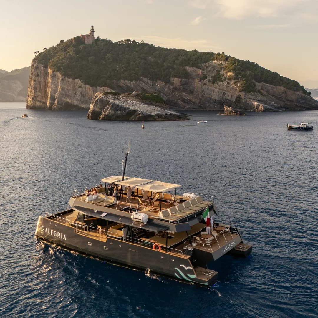 Il catamarano Alegria all'ancora nel golfo, con l'isola sullo sfondo nella foschia