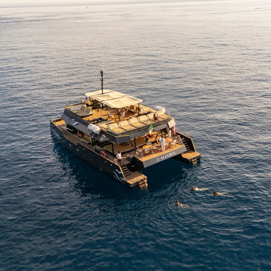 Il catamarano Alegria all'ancora sul blu profondo al largo, ripreso dal drone