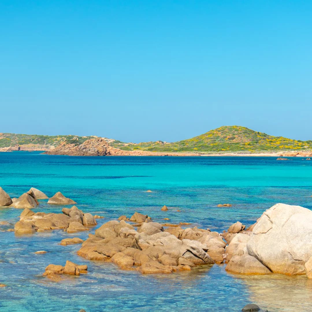 Rocce di granito sull'acqua bassa con le isole sullo sfondo