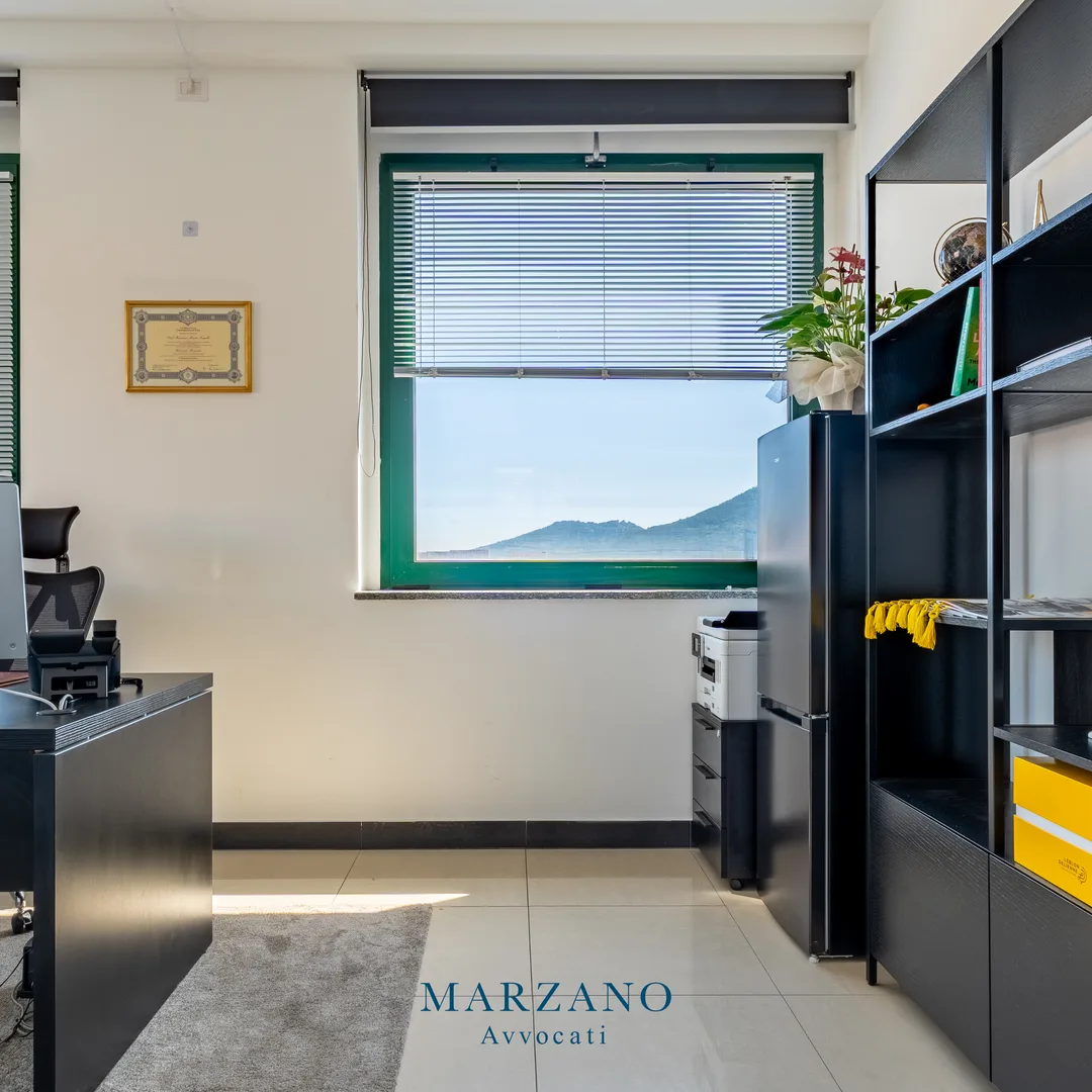 Ufficio dello studio con scrivania, libreria nera e vista sulle colline