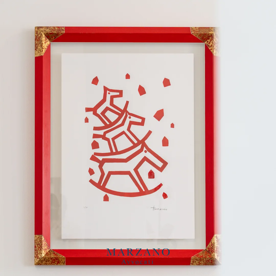 Stampa d'arte con cornice rossa appesa alla parete bianca dello studio