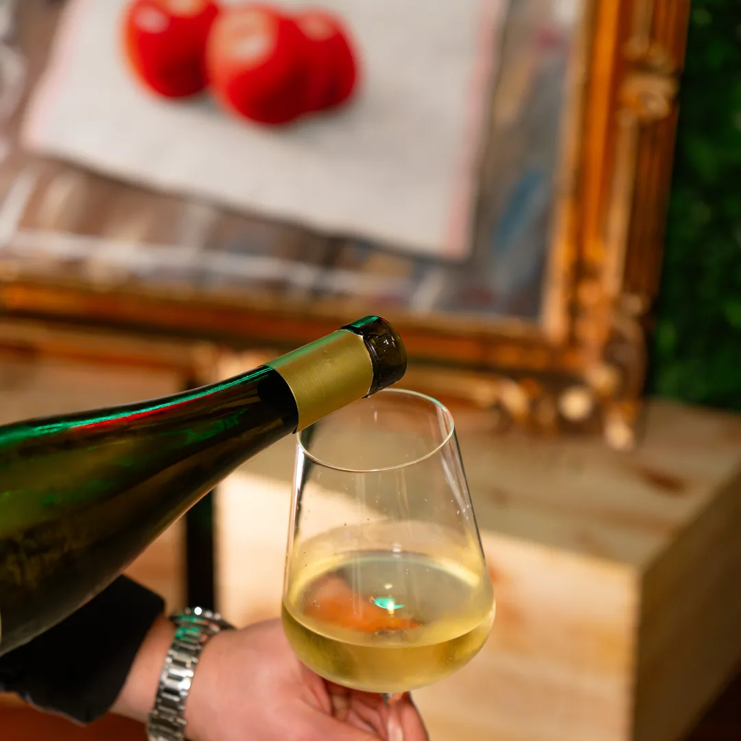 Bottiglia di bianco che riempie il calice, al tavolo del bistrot