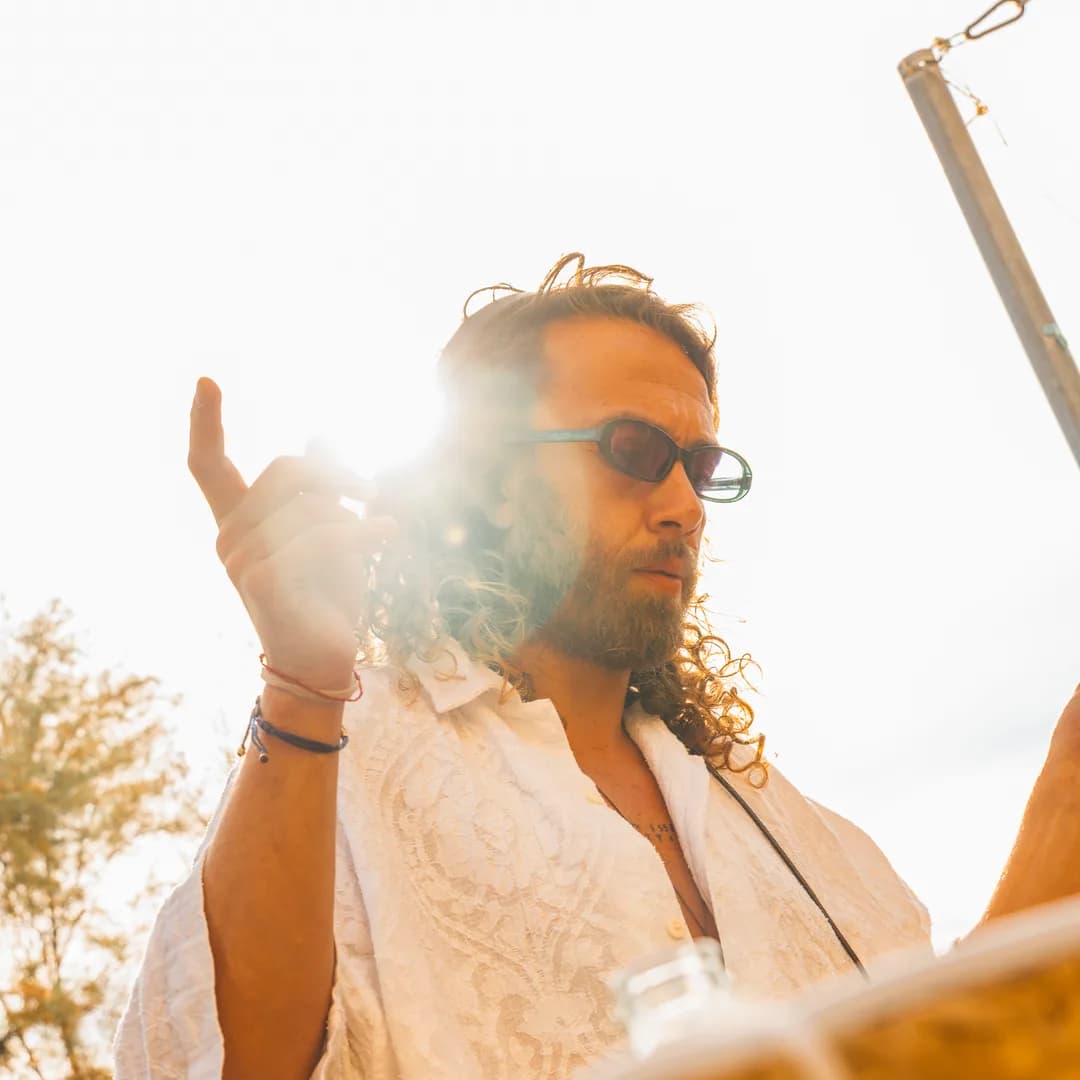 Ritratto di un dj in controluce, con il braccio alzato verso il pubblico